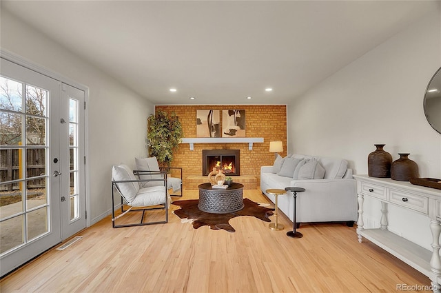 living area with visible vents, recessed lighting, a fireplace, and wood finished floors