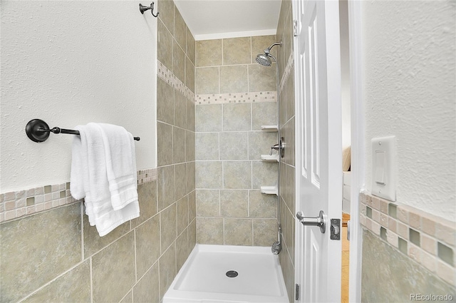 bathroom with a shower stall and a textured wall