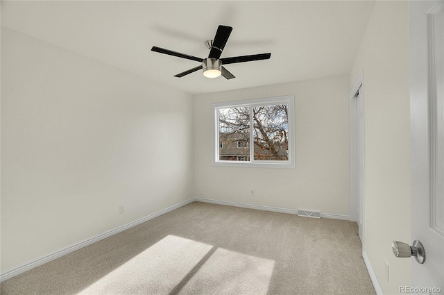 spare room with visible vents, light carpet, baseboards, and ceiling fan