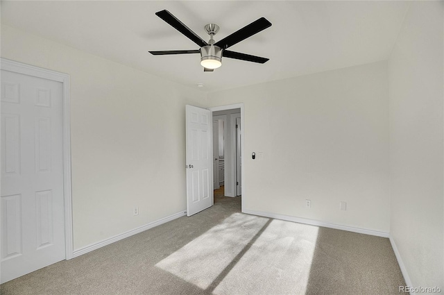 carpeted empty room with a ceiling fan and baseboards