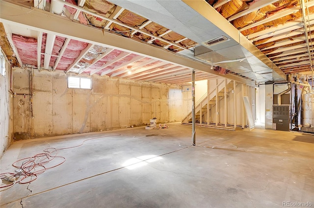 basement featuring stairway, heating unit, and visible vents