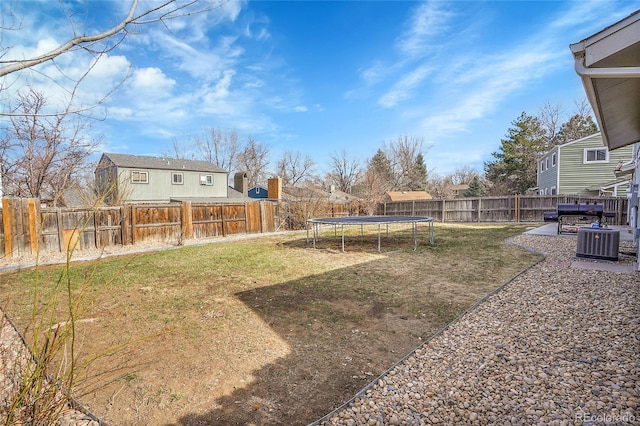 view of yard featuring a trampoline, cooling unit, and a fenced backyard