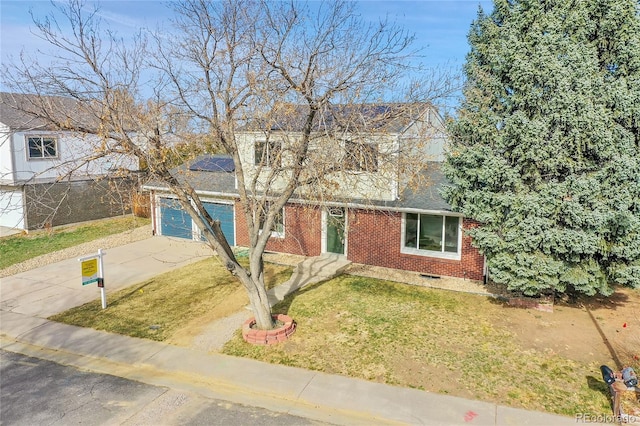 view of front of property with roof mounted solar panels, concrete driveway, an attached garage, a front yard, and brick siding