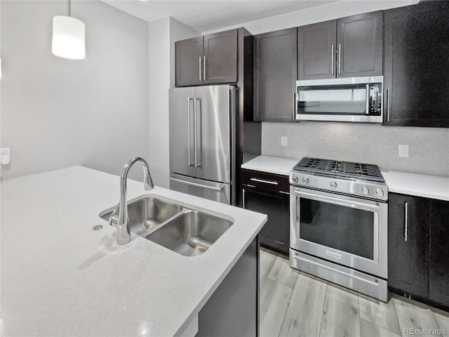 1245 Utica St Unit 104, Denver, CO 80204 - kitchen featuring appliances with stainless steel finishes, light countertops, decorative backsplash, hanging light fixtures, and light wood-style flooring