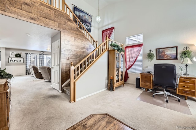 office area with carpet flooring, wood walls, and high vaulted ceiling