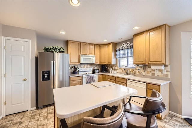 kitchen featuring white appliances, sink, light brown cabinetry, and tasteful backsplash