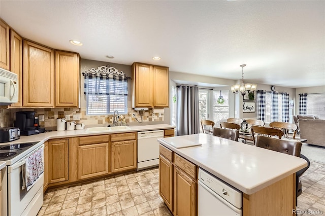 kitchen with white appliances, sink, decorative light fixtures, a chandelier, and a center island