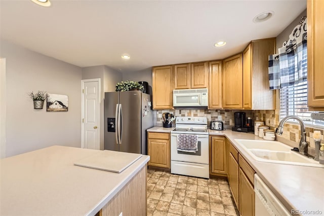 kitchen with light brown cabinets, white appliances, sink, and tasteful backsplash