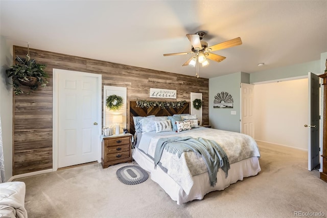 bedroom featuring ceiling fan, light colored carpet, and wooden walls