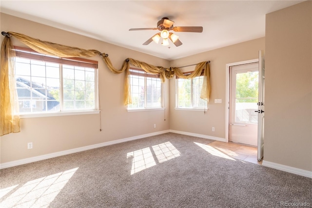 empty room featuring ceiling fan, a wealth of natural light, and light colored carpet