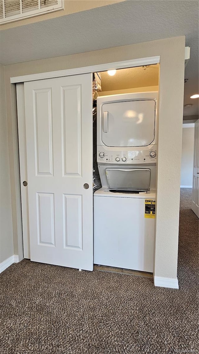 clothes washing area featuring stacked washer / drying machine and dark carpet