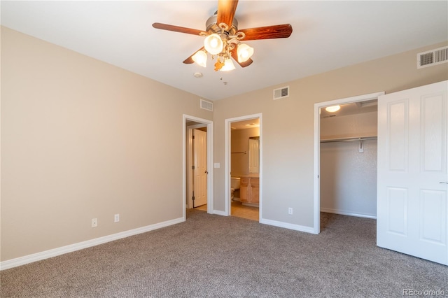 unfurnished bedroom featuring connected bathroom, a closet, carpet flooring, and ceiling fan