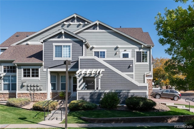 view of front of home with roof with shingles and stone siding