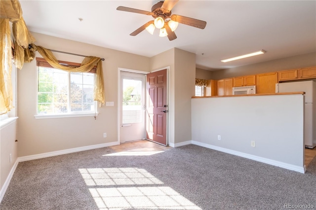 interior space with a ceiling fan, baseboards, light colored carpet, and plenty of natural light