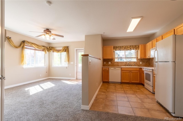 kitchen with a sink, white appliances, a ceiling fan, baseboards, and backsplash