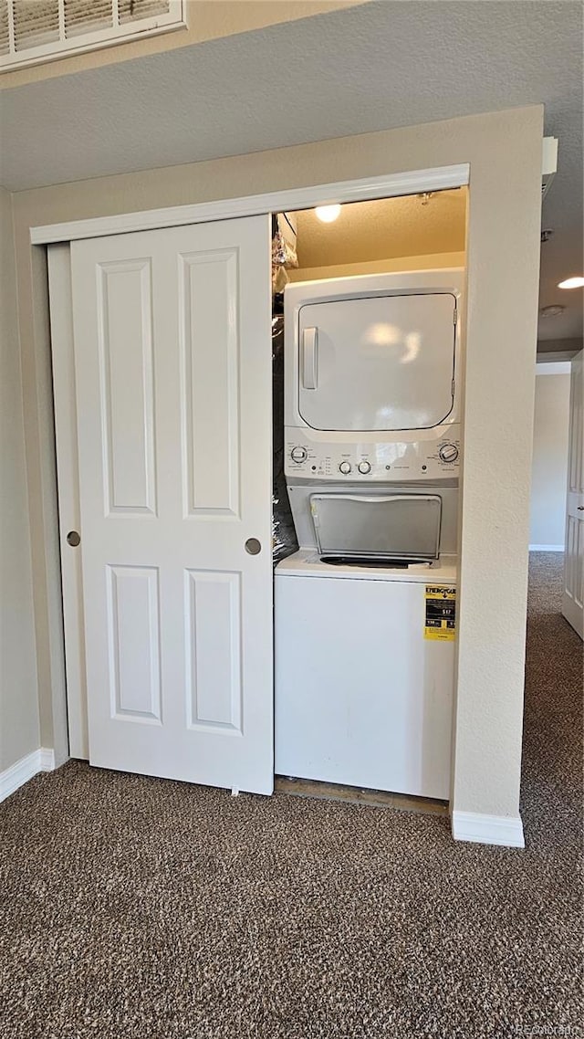 clothes washing area with laundry area, stacked washer and clothes dryer, and baseboards