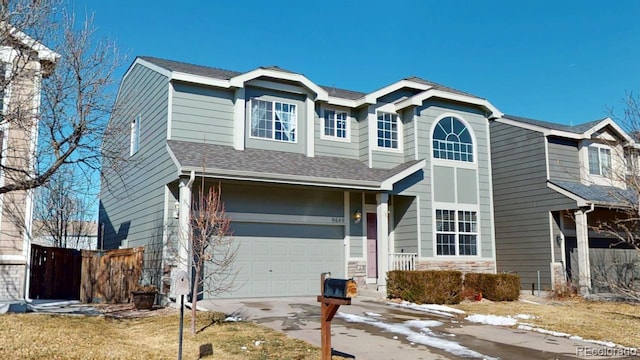 traditional-style home featuring a garage, fence, stone siding, concrete driveway, and roof with shingles