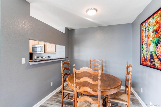 dining area with light wood-type flooring and baseboards