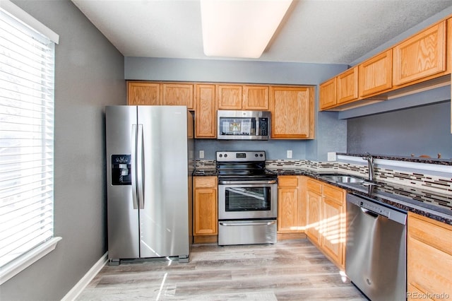 kitchen with a wealth of natural light, light wood finished floors, stainless steel appliances, and a sink