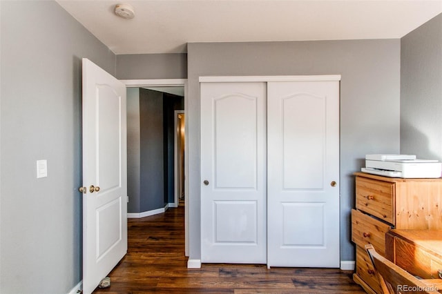 bedroom with a closet, baseboards, and dark wood-style flooring