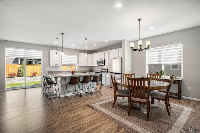dining area with recessed lighting, wood finished floors, baseboards, and a notable chandelier