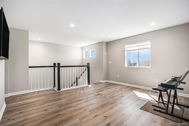interior space with baseboards, wood finished floors, an upstairs landing, and recessed lighting