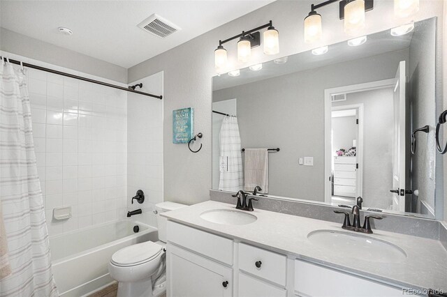 bathroom with double vanity, visible vents, toilet, and a sink