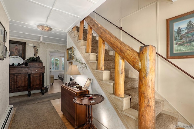 stairway with baseboard heating and hardwood / wood-style floors