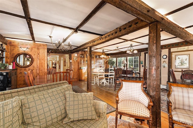 living room with coffered ceiling, beam ceiling, wood-type flooring, a notable chandelier, and wood walls