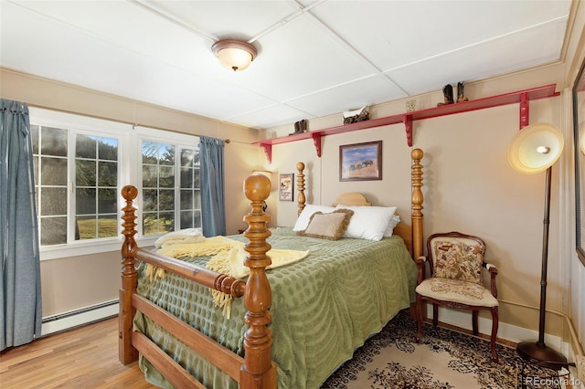 bedroom featuring wood-type flooring and a baseboard heating unit