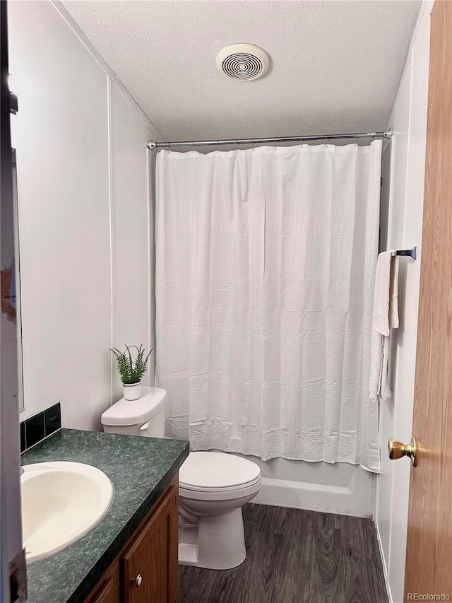 full bathroom with toilet, wood finished floors, vanity, a textured ceiling, and visible vents