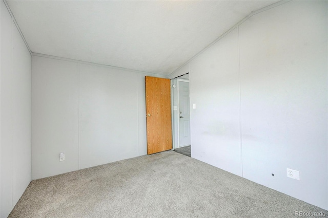 carpeted spare room with vaulted ceiling
