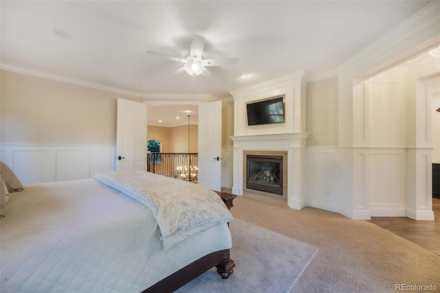 16092 Waving Branch Way, Colorado Springs, CO 80908 - bedroom featuring a decorative wall, a glass covered fireplace, a wainscoted wall, ornamental molding, and light carpet