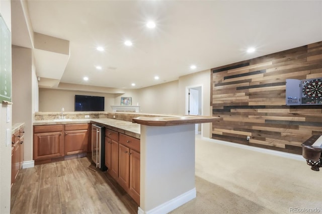 16092 Waving Branch Way, Colorado Springs, CO 80908 - kitchen with brown cabinetry, a sink, a peninsula, beverage cooler, and wooden walls