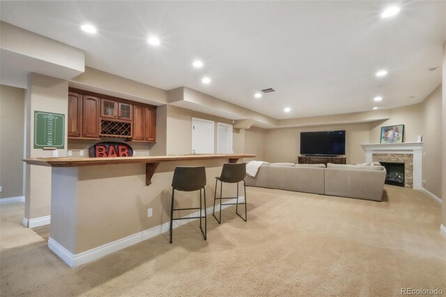16092 Waving Branch Way, Colorado Springs, CO 80908 - kitchen featuring light carpet, a breakfast bar area, baseboards, brown cabinetry, and recessed lighting