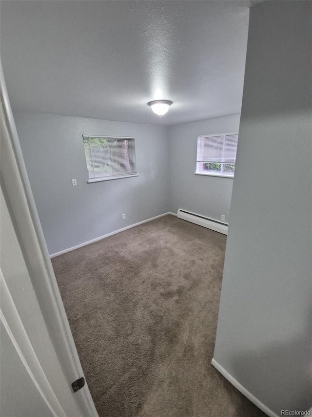 387 Tucson St, Aurora, CO 80011 - spare room with a baseboard heating unit, dark colored carpet, and baseboards