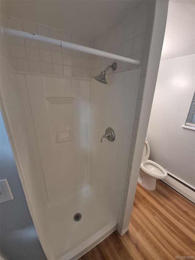 387 Tucson St, Aurora, CO 80011 - full bathroom with toilet, wood finished floors, a stall shower, and a baseboard heating unit