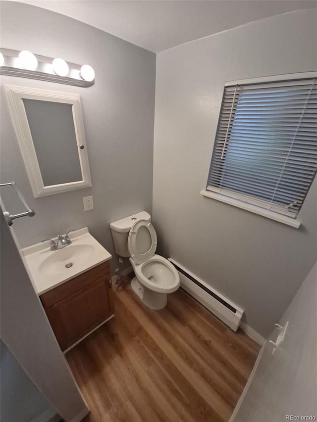 387 Tucson St, Aurora, CO 80011 - bathroom featuring a baseboard radiator, wood finished floors, toilet, and vanity
