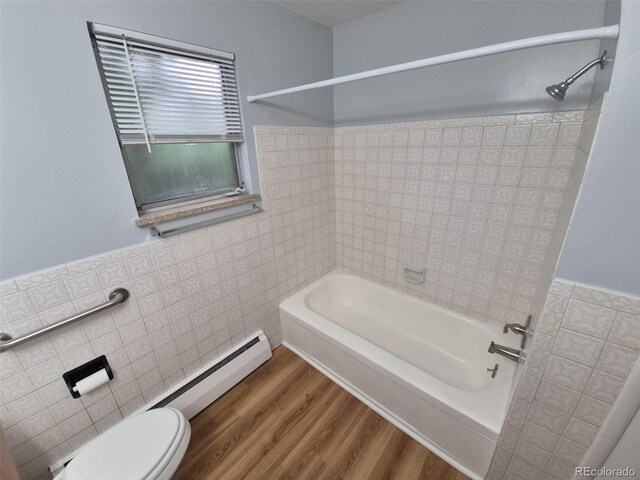 387 Tucson St, Aurora, CO 80011 - bathroom with tile walls, washtub / shower combination, toilet, wainscoting, and a baseboard heating unit
