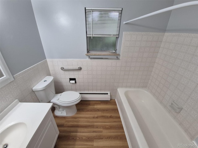 387 Tucson St, Aurora, CO 80011 - bathroom featuring tile walls, a baseboard radiator, a bathtub, toilet, and wainscoting