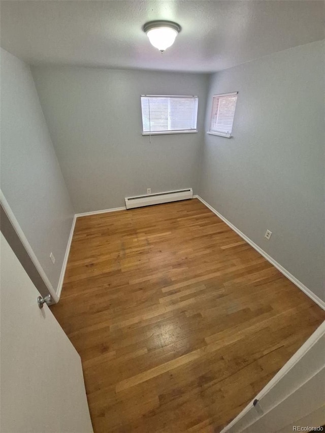 387 Tucson St, Aurora, CO 80011 - empty room featuring a baseboard radiator, wood finished floors, and baseboards