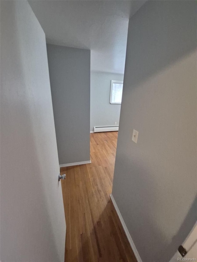 387 Tucson St, Aurora, CO 80011 - corridor featuring a baseboard radiator, wood finished floors, and baseboards
