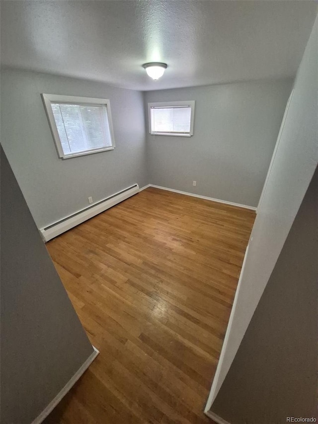 387 Tucson St, Aurora, CO 80011 - spare room featuring a baseboard radiator, wood finished floors, and baseboards