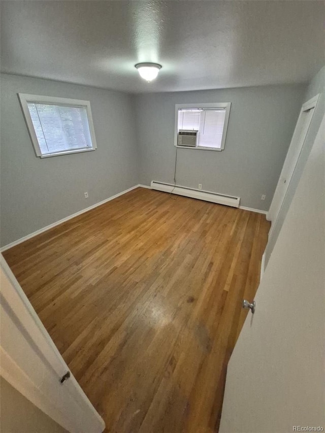387 Tucson St, Aurora, CO 80011 - unfurnished bedroom featuring a baseboard radiator, wood finished floors, and baseboards