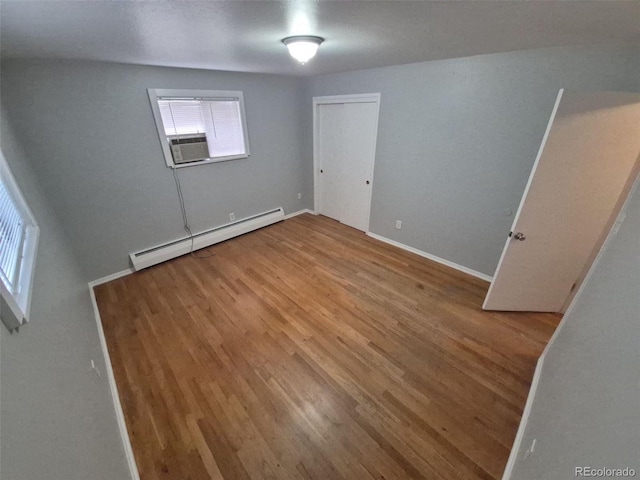 387 Tucson St, Aurora, CO 80011 - unfurnished bedroom with a baseboard radiator, wood finished floors, cooling unit, and baseboards