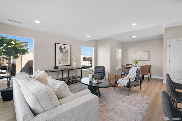 living area with light wood finished floors, visible vents, recessed lighting, and baseboards