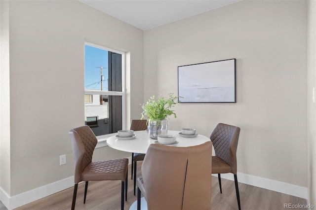 dining space featuring baseboards and wood finished floors