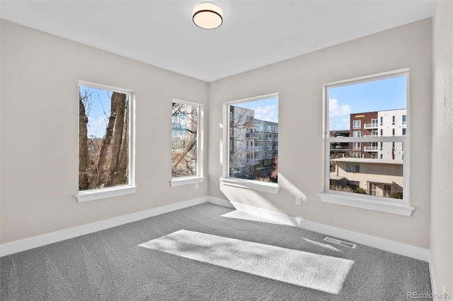 carpeted empty room with baseboards, visible vents, and a wealth of natural light