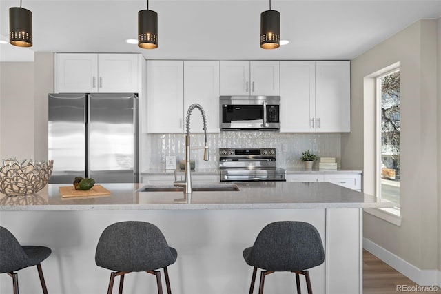 kitchen featuring stainless steel appliances, white cabinetry, and pendant lighting