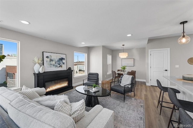 living room with a glass covered fireplace, baseboards, recessed lighting, and wood finished floors
